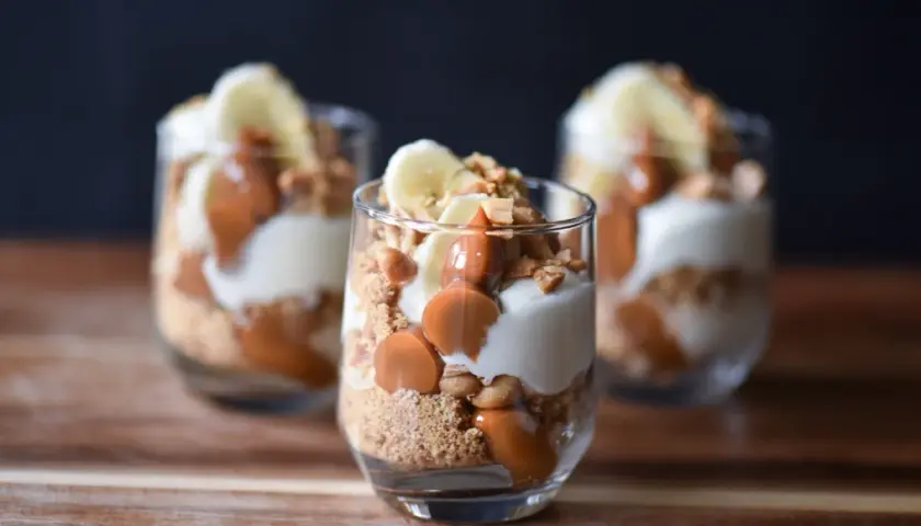 Tre glas med banoffee paj i lager av kexsmulor, krämig fyllning, banan och kolasås.