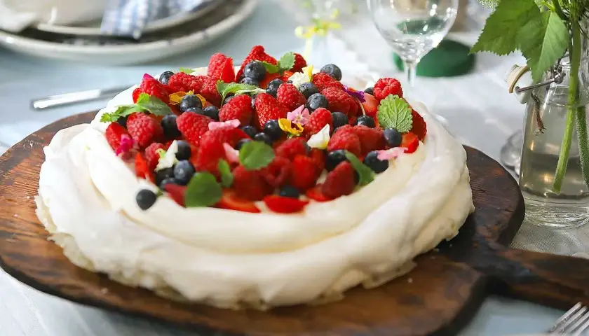 En vacker pavlova med grädde och färska bär, perfekt för ett sommarfika. Ett enkelt pavlova recept att följa.