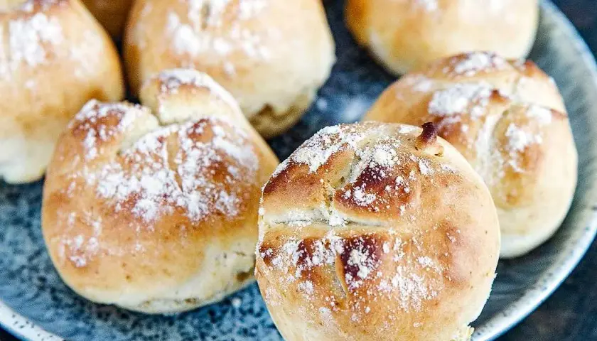Färska, gyllene 10 minuters frallor, pudrade med mjöl, ligger på en blå tallrik. Perfekta för en snabb frukost eller fika.