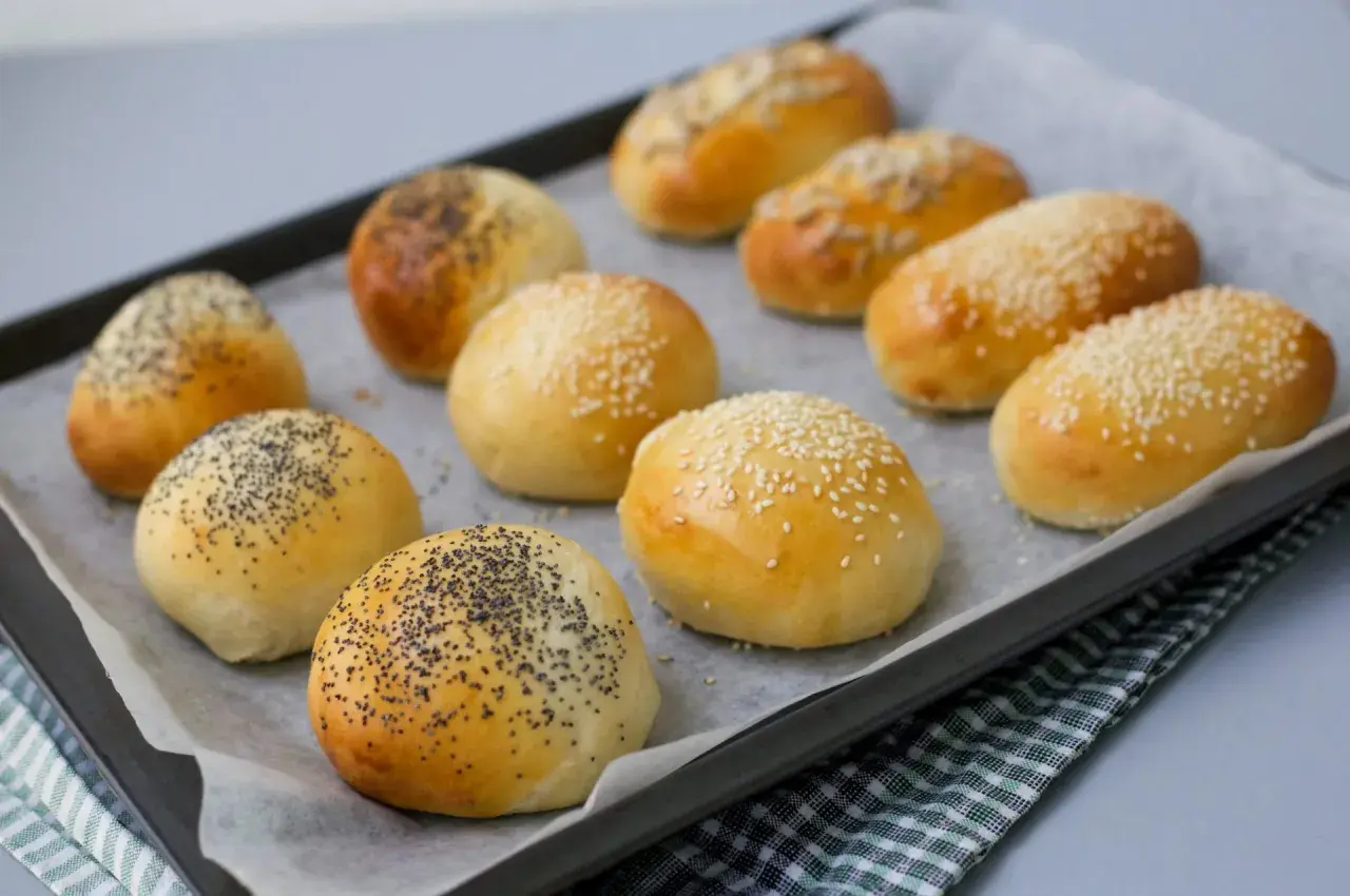 Nybakade bakpulver frallor med vallmofrön och sesamfrön på en plåt. Perfekta för frukost eller fika.