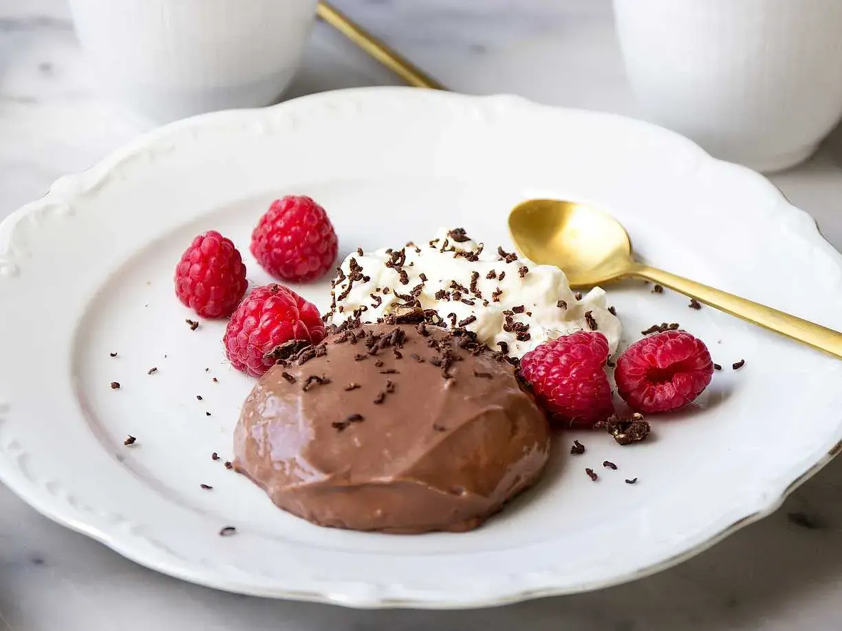 En krämig chokladpudding med hallon och vispad grädde, perfekt för ett enkelt chokladpudding recept.