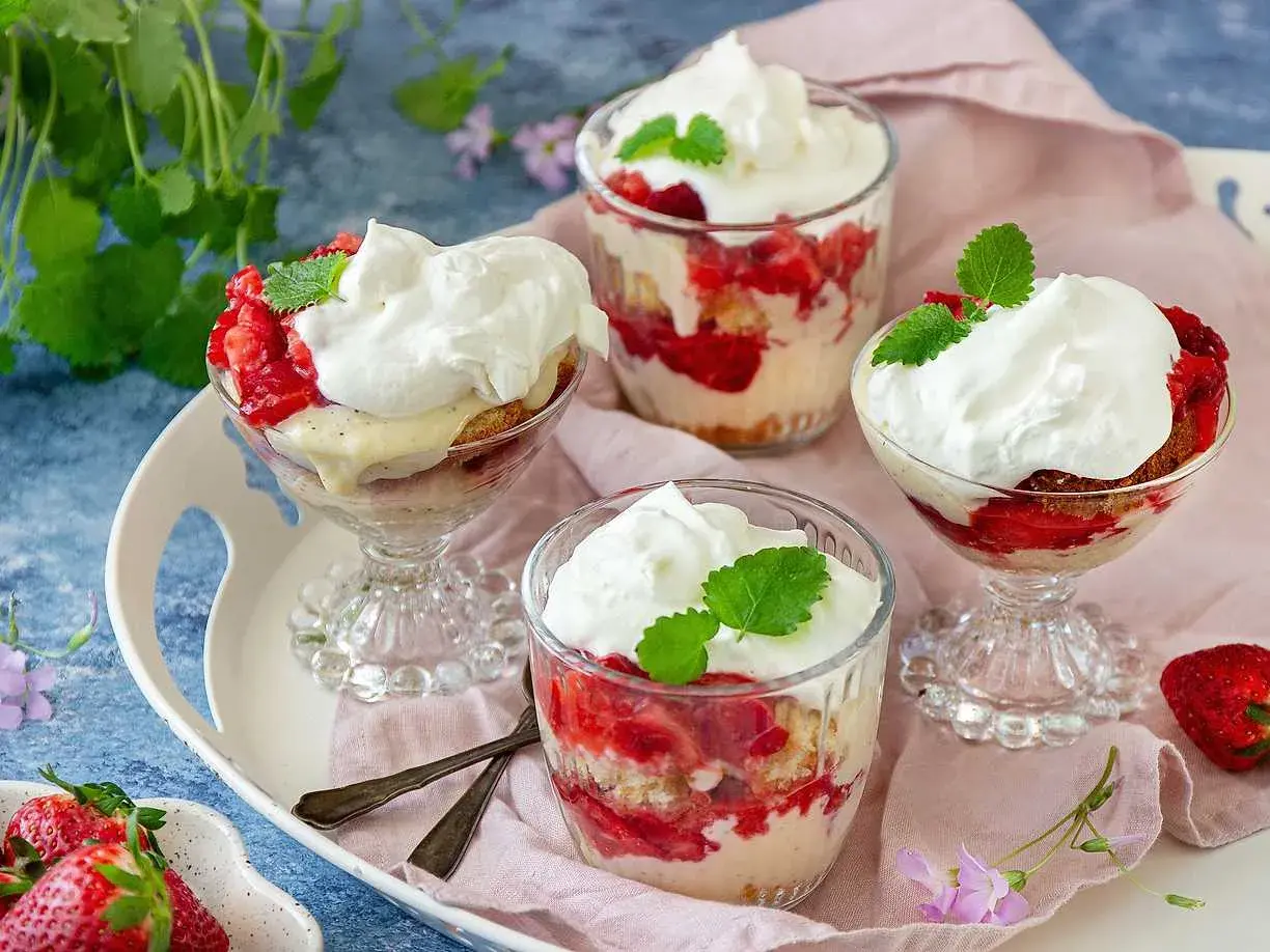 Ljuvlig jordgubbstårta i glas, lager av sockerkaka, färska jordgubbar och vispgrädde. Perfekt sommardessert.