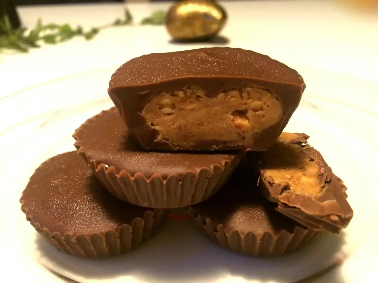 En hög med chokladkoppar med jordnötssmörsfyllning. En är uppskuren och visar den krämiga fyllningen.