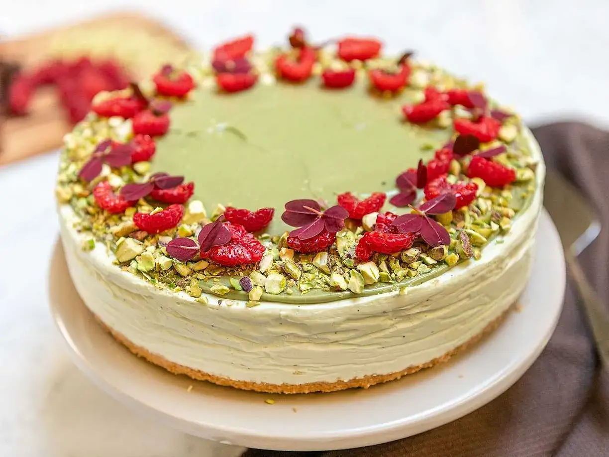 En krämig pistage cheesecake, dekorerad med hallon och pistagenötter. En dröm för alla sötsugna!