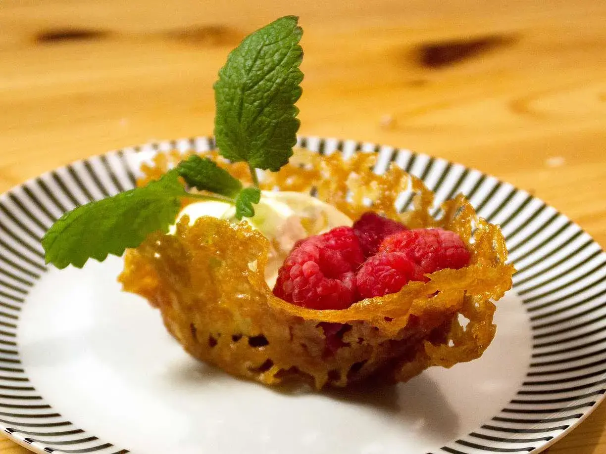 En dessert med glass, hallon och mynta i en krispig knäckflarnskorg. Perfekt till glass!