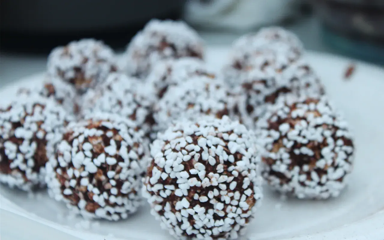 En tallrik med chokladbollar, perfekta för ett enkelt chokladbollar recept. De är rullade i kokosflingor.