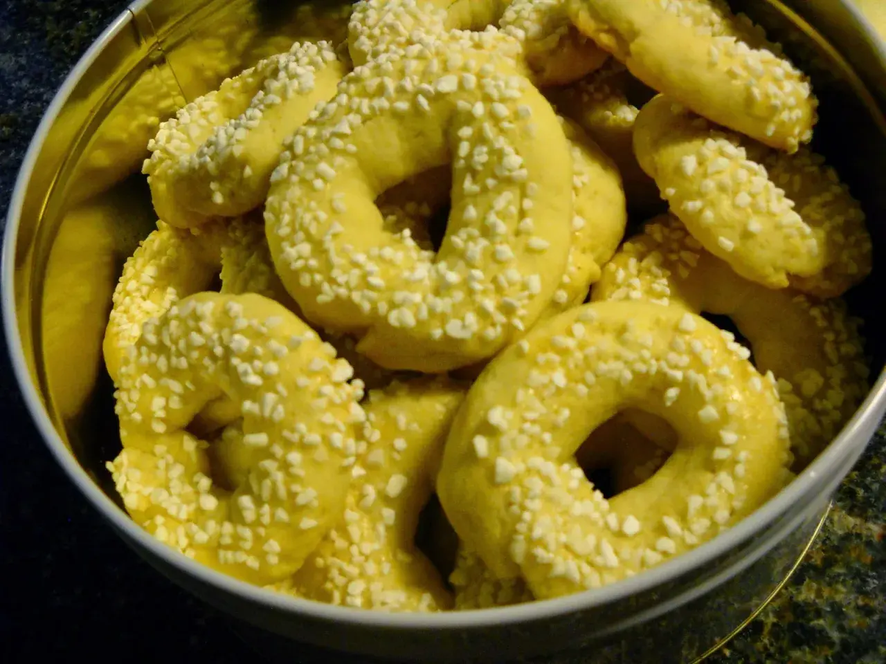 En burk fylld med gyllene kringlor med bakpulver, strösslade med små vita bitar.