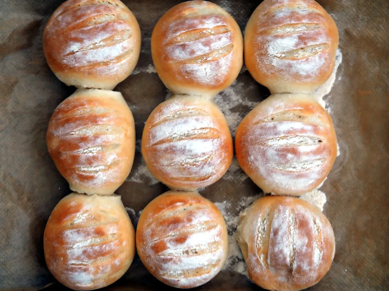 Nio nybakade vetekakor, pudrade med mjöl, redo att avnjutas. Ett perfekt vetekaka recept för hembakat bröd.