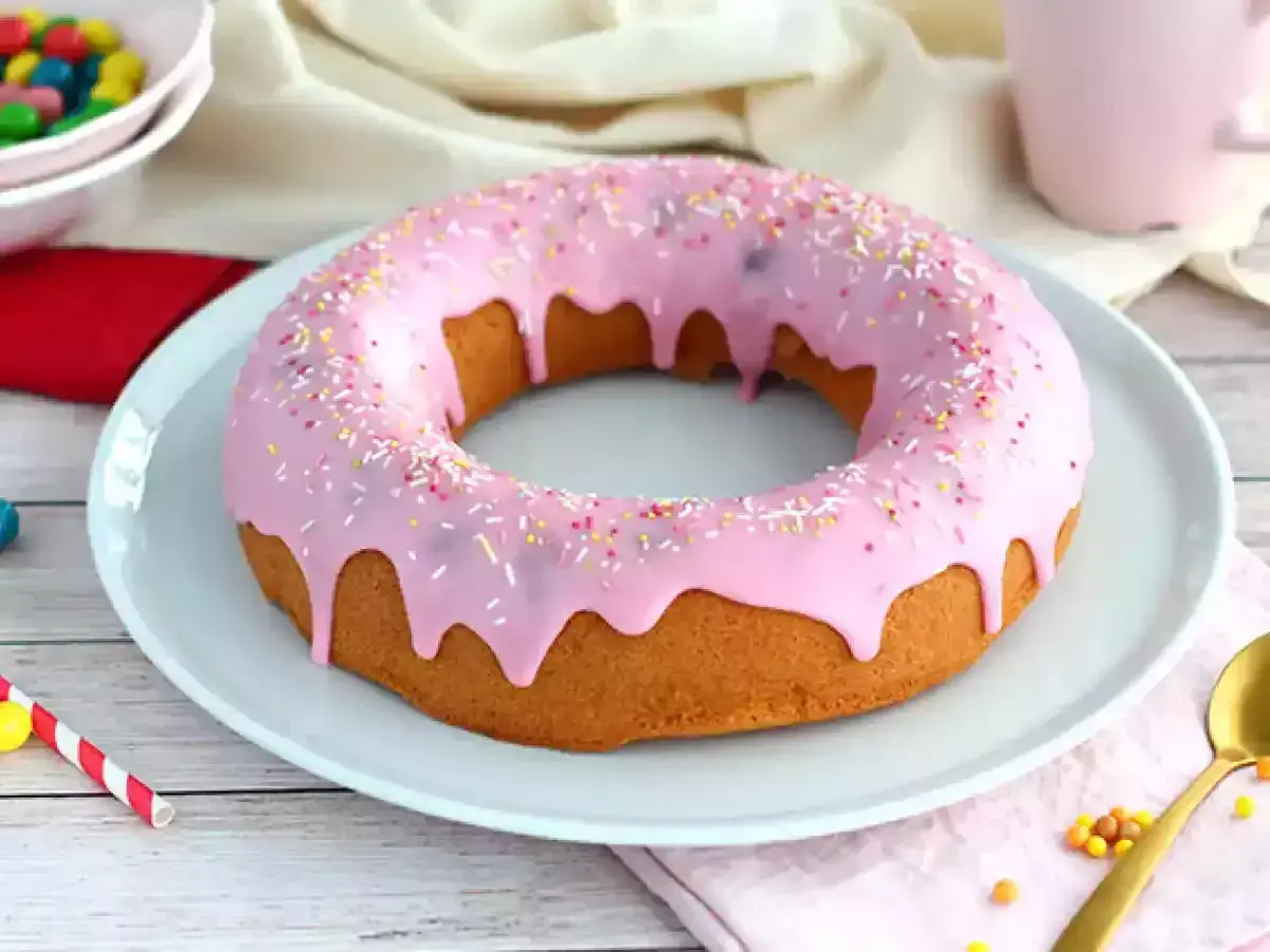 En stor donut tårta med rosa glasyr och strössel. Perfekt för ett kalas!