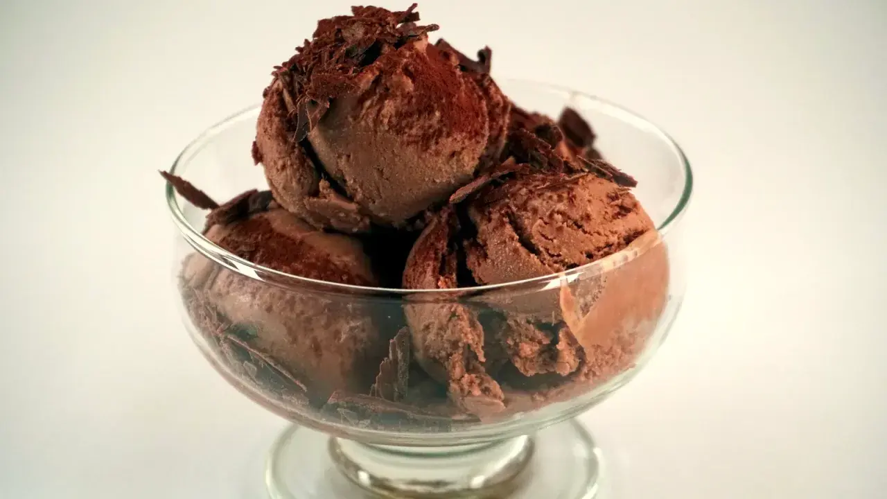 En skål med krämig chokladglass, toppad med chokladspån. Perfekt för ett enkelt chokladglass recept.