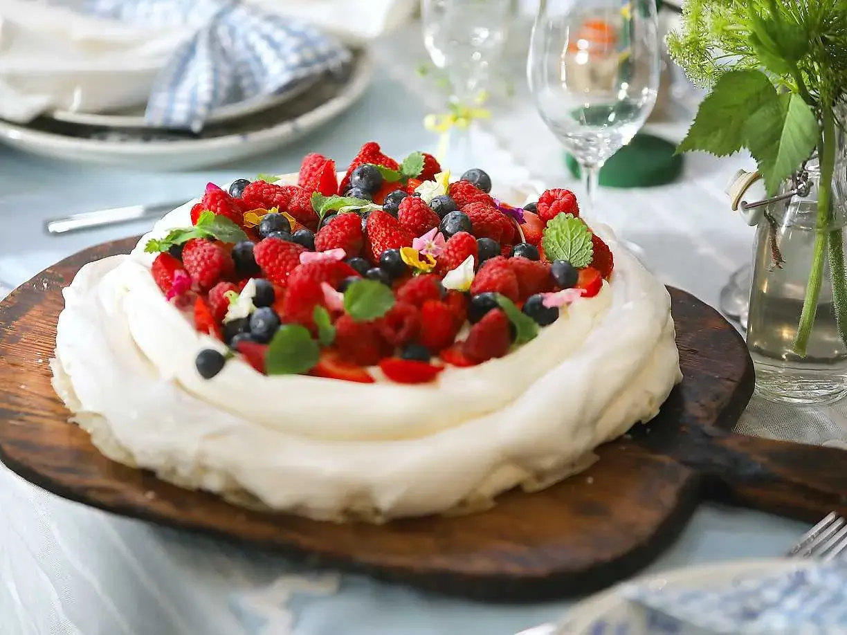 En vacker pavlova med grädde och färska bär, perfekt för ett sommarfika. Ett enkelt pavlova recept att följa.
