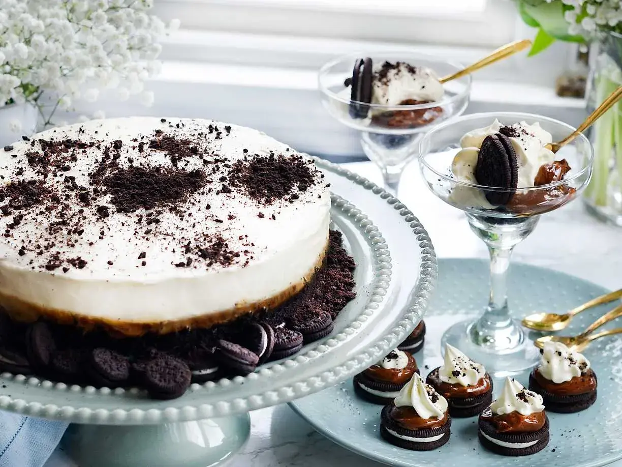 En krämig oreo cheesecake med krossade oreos på toppen. Serveras med små oreo-desserter och i glas.