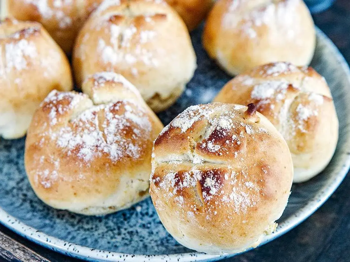 Färska, gyllene 10 minuters frallor, pudrade med mjöl, ligger på en blå tallrik. Perfekta för en snabb frukost eller fika.