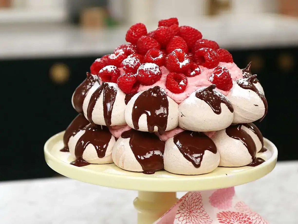 En stapel mar&auml;nger med chokladglasyr, hallon och rosa gr&auml;dde. En h&auml;rlig pavlova choklad som ser uts&ouml;kt ut.