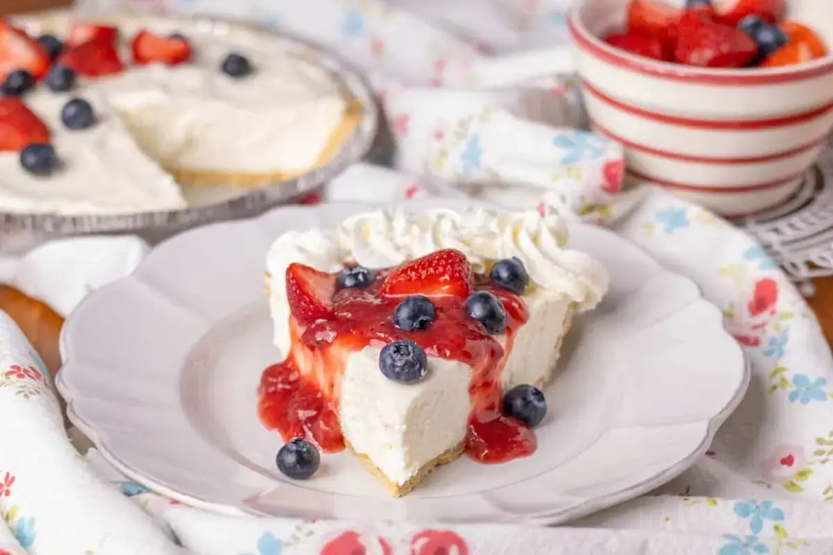 En kr&auml;mig cheesecake utan ugn, toppad med f&auml;rska jordgubbar, bl&aring;b&auml;r och en h&auml;rlig jordgubbss&aring;s. Perfekt f&ouml;r sommaren!