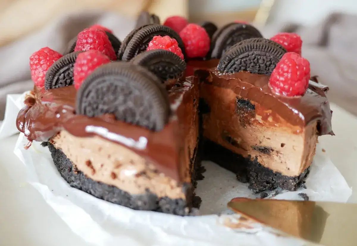En lyxig choklad cheesecake med Oreos och hallon, redo att skäras.