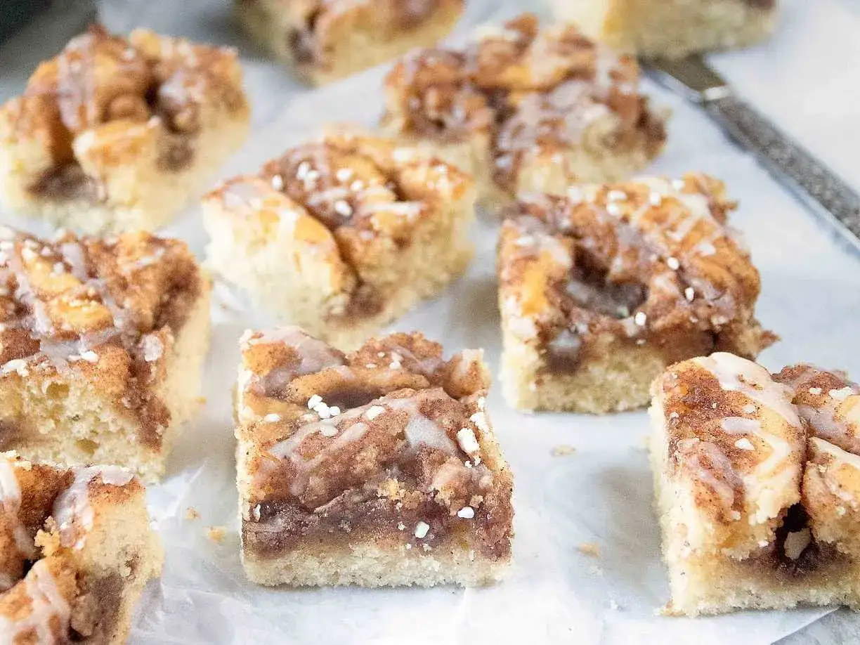 Kanelbullekaka i l&aring;ngpanna, skuren i fyrkantiga bitar med socker och kanel.