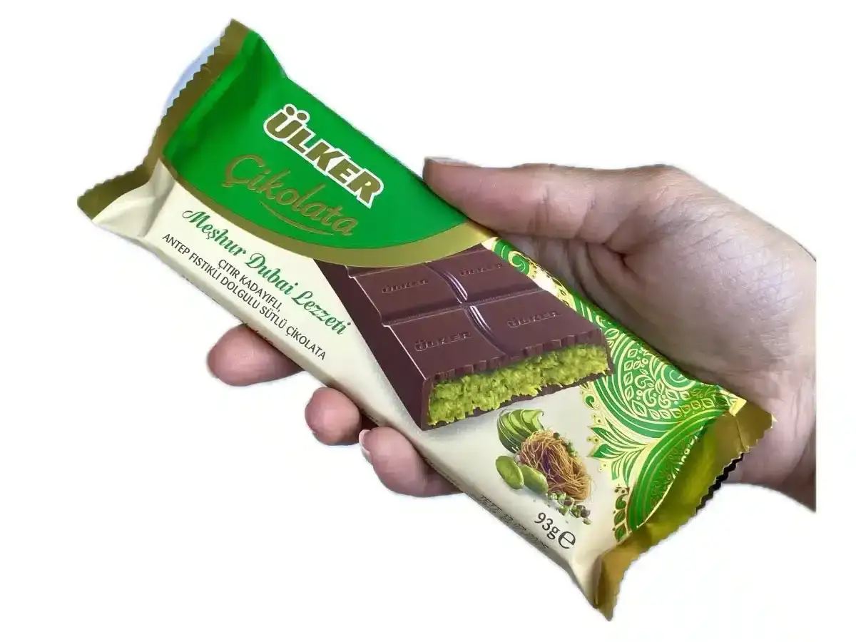 En hand håller en Ülker chokladkaka med pistagefyllning, inspirerad av ett dubai choklad recept.