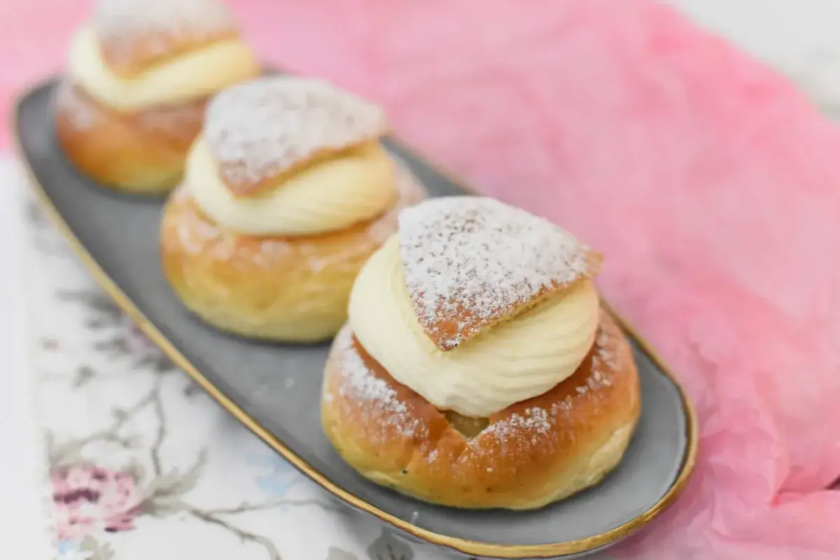 Tre semlor p&aring; ett fat, redo att avnjutas. Ett perfekt semmelt&aring;rta recept f&ouml;r fika.