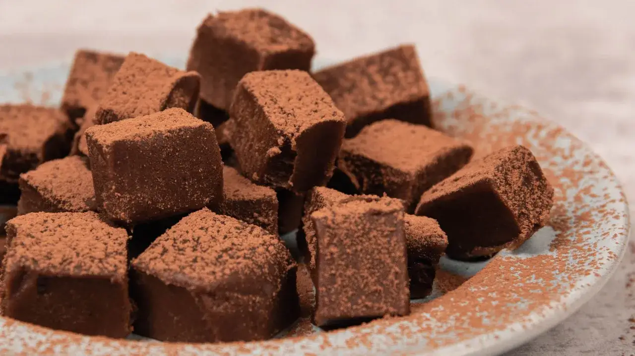 En h&ouml;g med choklad fudge, pudrad med kakao, ligger p&aring; en ljusbl&aring; tallrik.