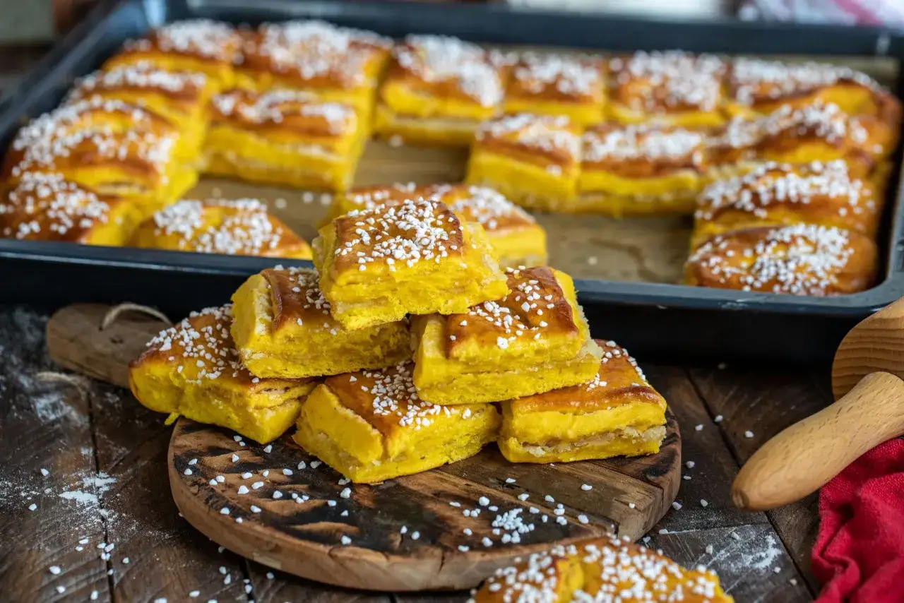 Gyllene lussebullar i l&aring;ngpanna, toppade med p&auml;rlsocker, redo att avnjutas. En h&auml;rlig syn f&ouml;r alla som &auml;lskar saffransbakverk.