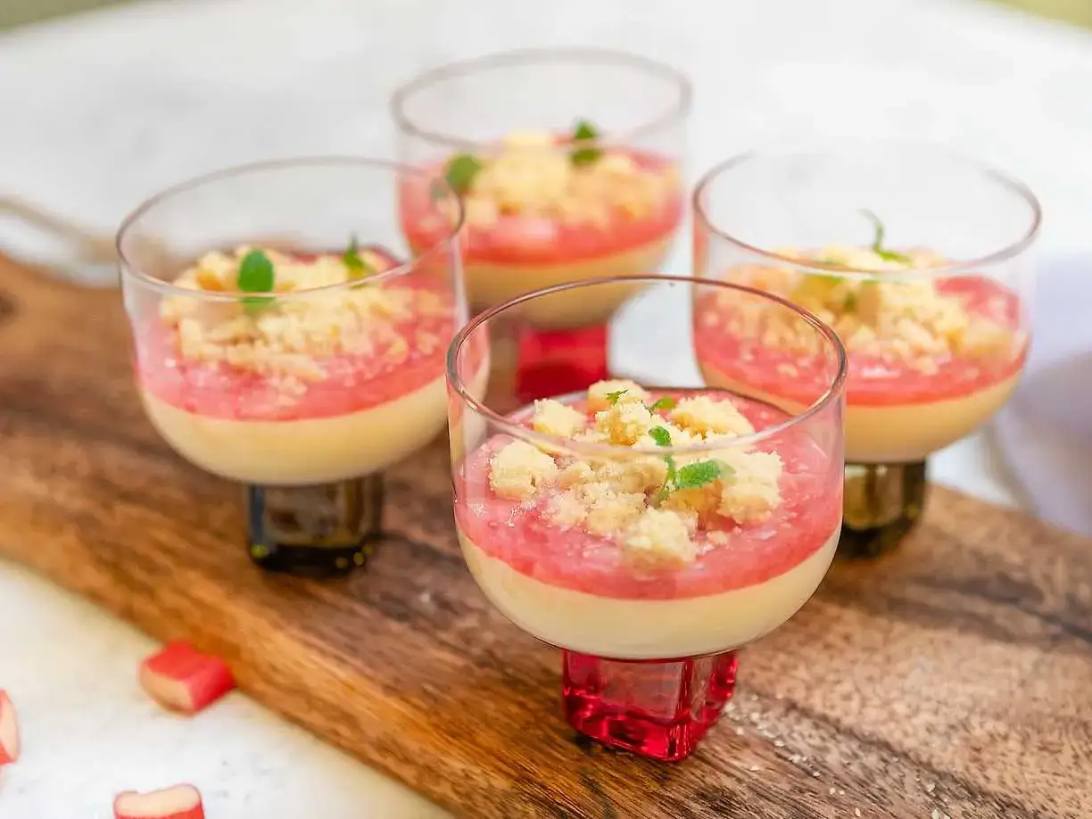 Fyra glas med kr&auml;mig pannacotta med rabarberkompott och smuldeg. Garnerad med mynta. En h&auml;rlig sommardessert.