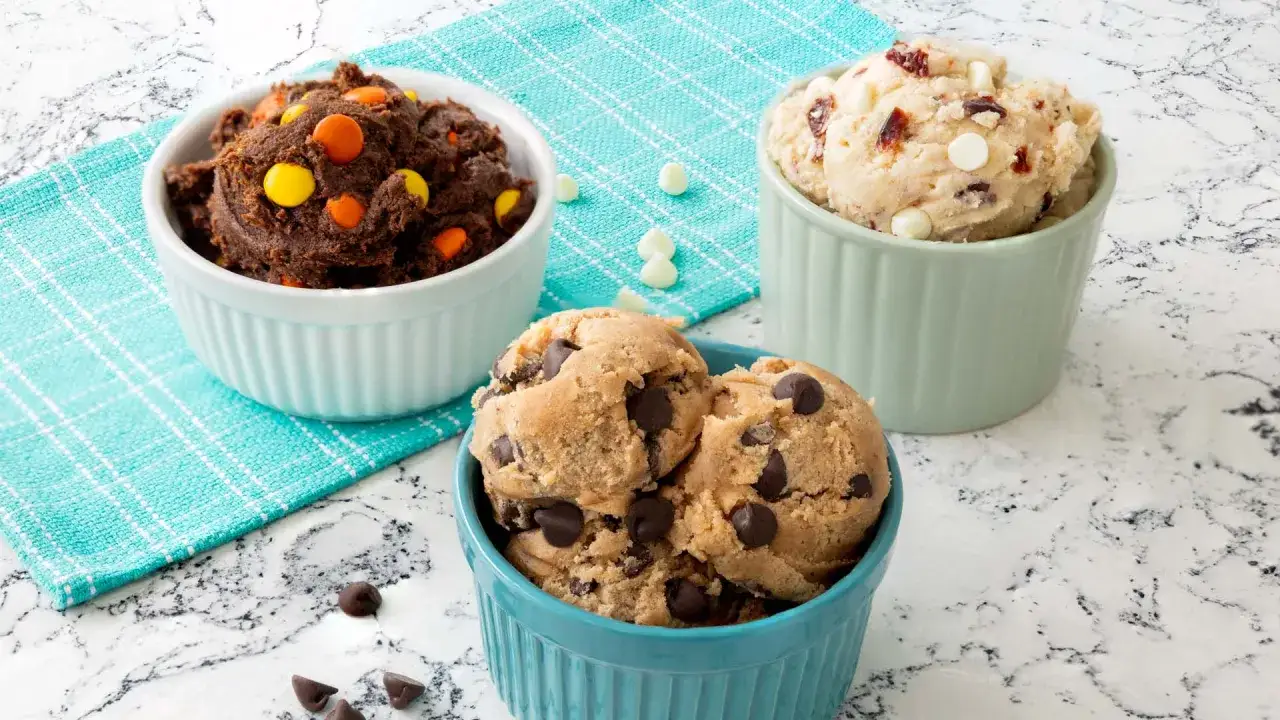 Tre skålar med olika cookie dough recept: choklad med godis, klassisk med chokladbitar och vit choklad med nötter.