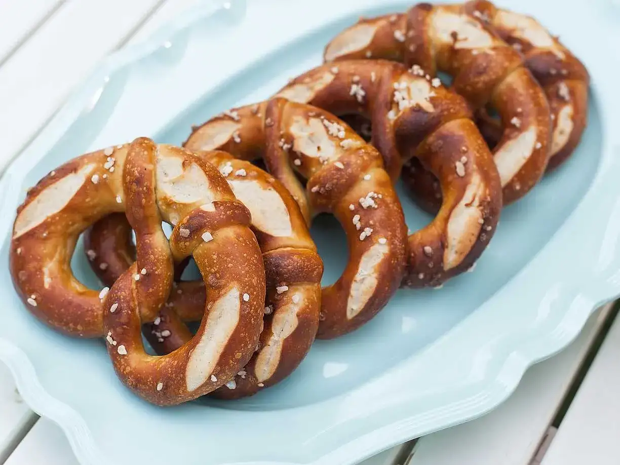 En ljusbl&aring; bricka med flera gyllenbruna kringlor, str&ouml;sslade med grovt salt. Perfekt f&ouml;r fika.