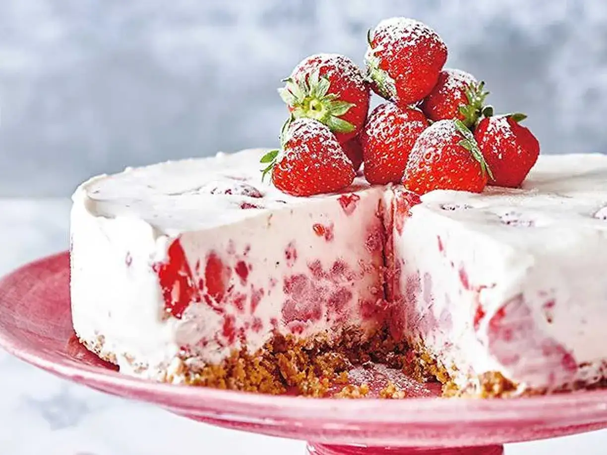 En krämig jordgubbs cheesecake med färska jordgubbar på toppen, pudrad med florsocker. En härlig sommardessert.